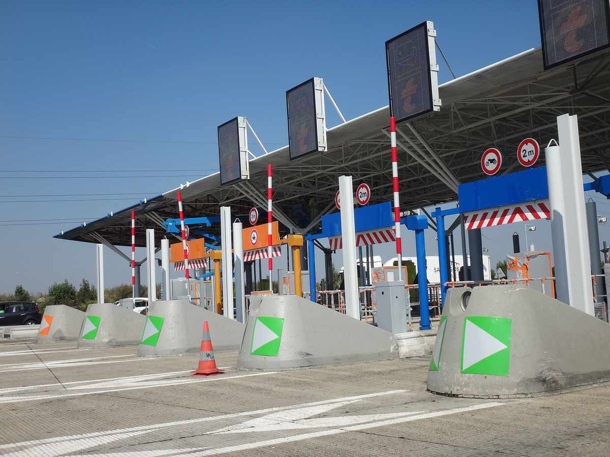 Allée de péage avec barrières, panneaux, cônes et véhicules