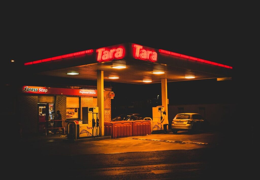 Station-service éclairée la nuit, voiture garée, enseigne rouge Tara Tara
