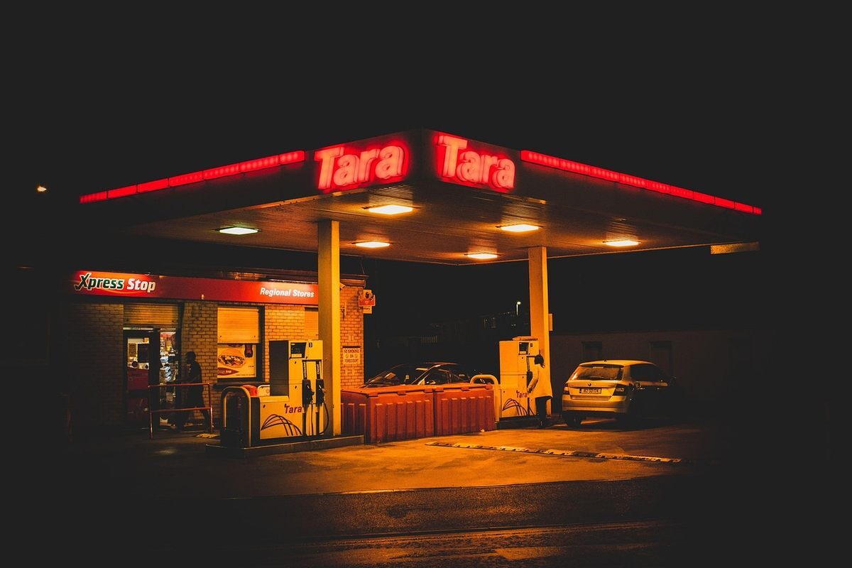 Station-service éclairée la nuit, voiture garée, enseigne rouge Tara Tara