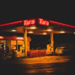 Station-service éclairée la nuit, voiture garée, enseigne rouge Tara Tara